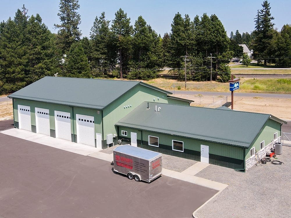 aerial view of a green commercial steel structure building with gray roof and 4 white overhead garage doors