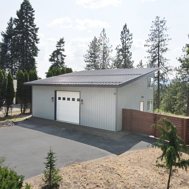 gray steel structure shop with a white overhead garage door