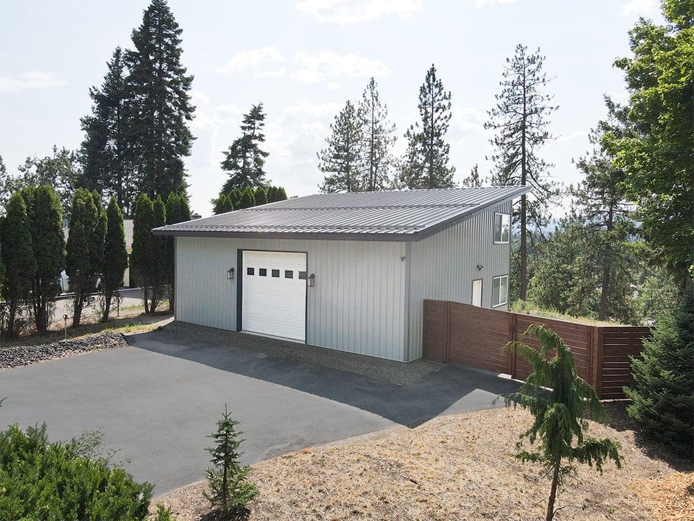 gray steel structure shop with a white overhead garage door