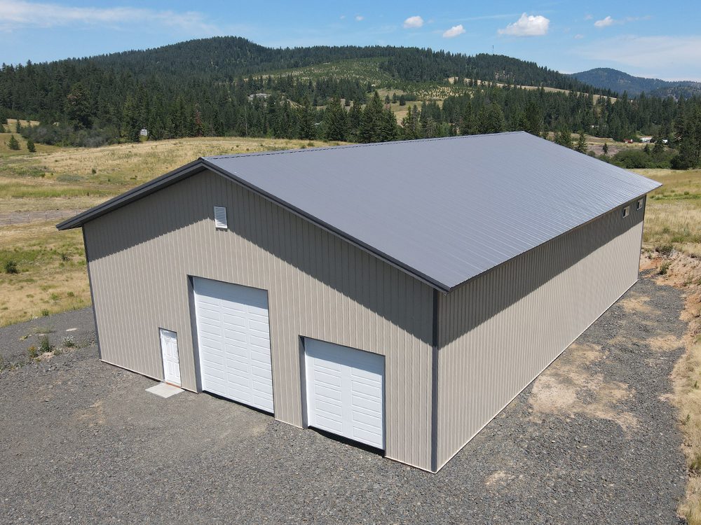 beige poll barn steel structure with 2 overhead garage doors