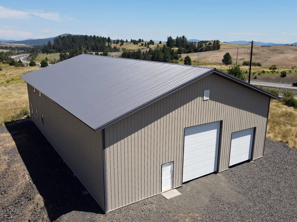 beige poll barn steel structure with 2 overhead garage doors