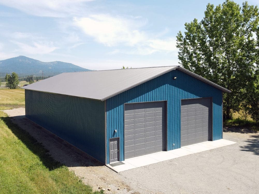 steel structure poll barn shop done in blue with 2 gray overhead garage doors