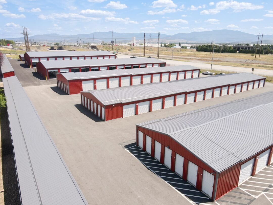 Steel structure storage facility done in red siding and grey roofing with white overhead doors