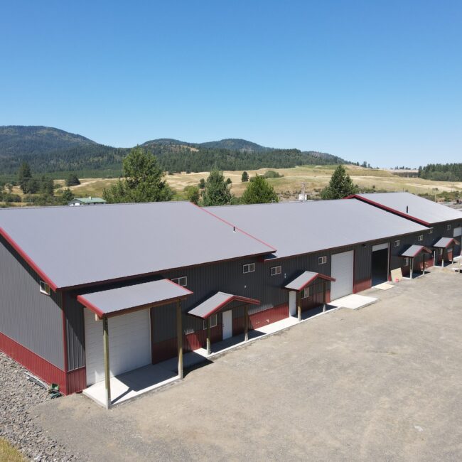 aerial view of a gray multi-use steel structure in Worley Idaho with red trim and white overhead garage doors