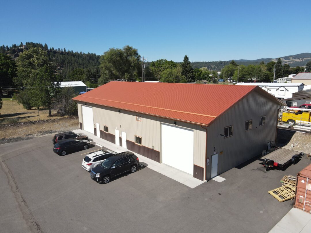 aerial view of steel structure commercial building with red roof and beige siding and white overhead doors