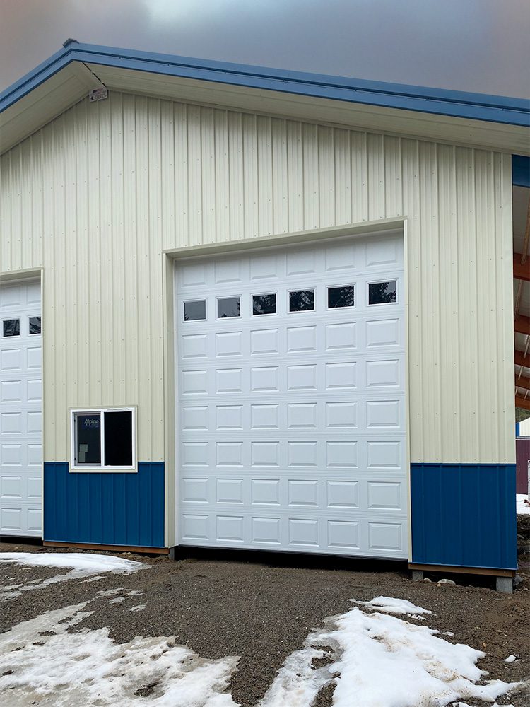 ivory garage with blue trim and white over-head garage doors