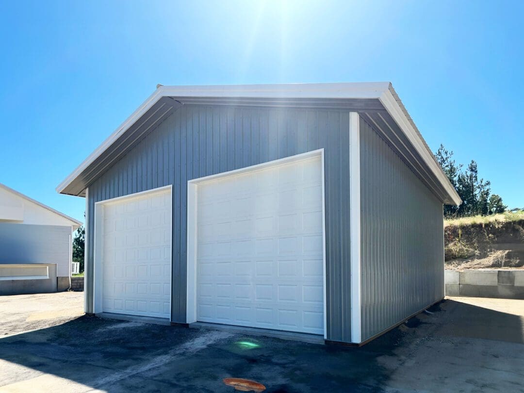 small gray workshop, with 2 white garage doors