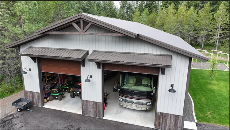 A pole barn shop has its large doors open to fit an RV and ATVs