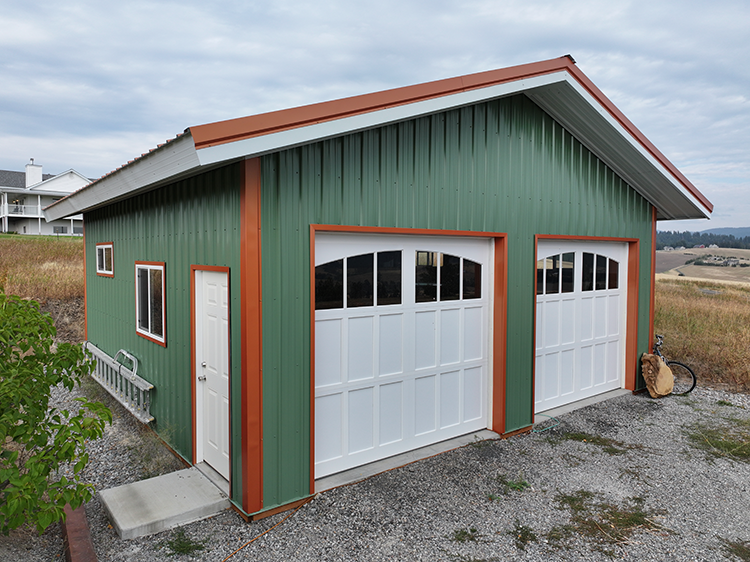 A 24x24 small metal building built by Steel Structures America. Green with orange trim and white doors