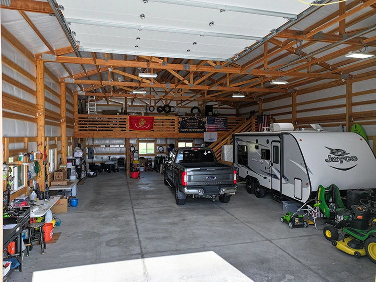 A camper is in a shop alongside a truck