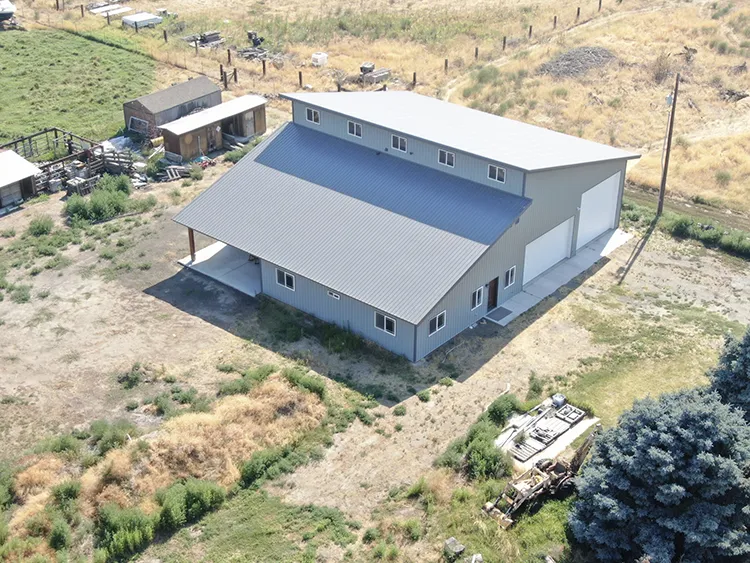A pole barn house in grey with a grey roof