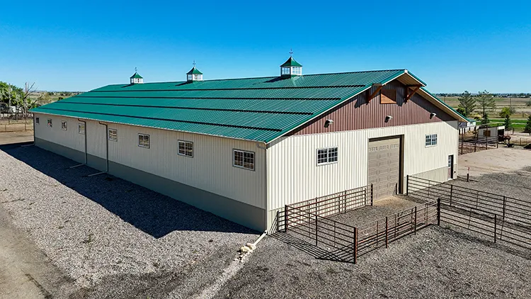 A cattle barn agricultural pole barn. White walls, and green roof, steel post-frame building