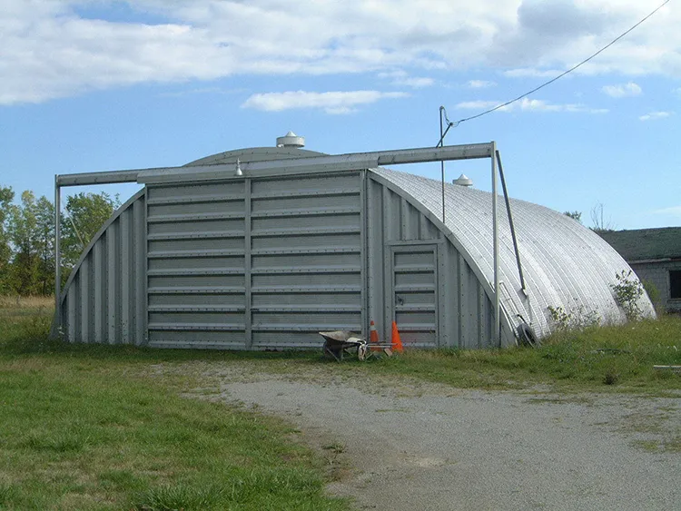 A quonset hut at the end of a dirt path