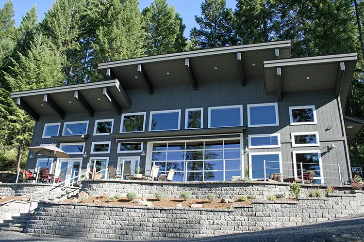 A grey two story barndominium with large windows